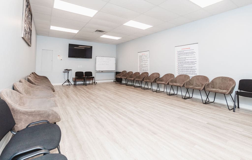 a room in a Mental Health Center Near New Jersey featuring a couch, chairs, and a projector screen