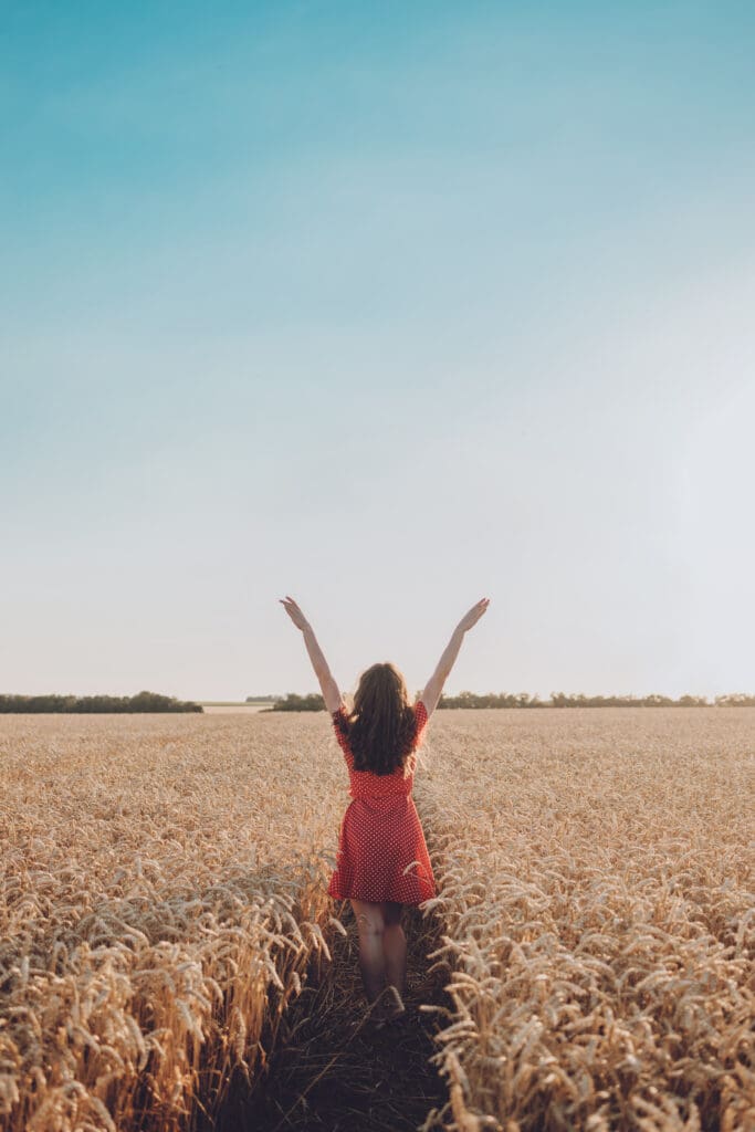 a woman in a red dress is standing in a wheat field, symbolizing the importance of mental health support and care in New Jersey