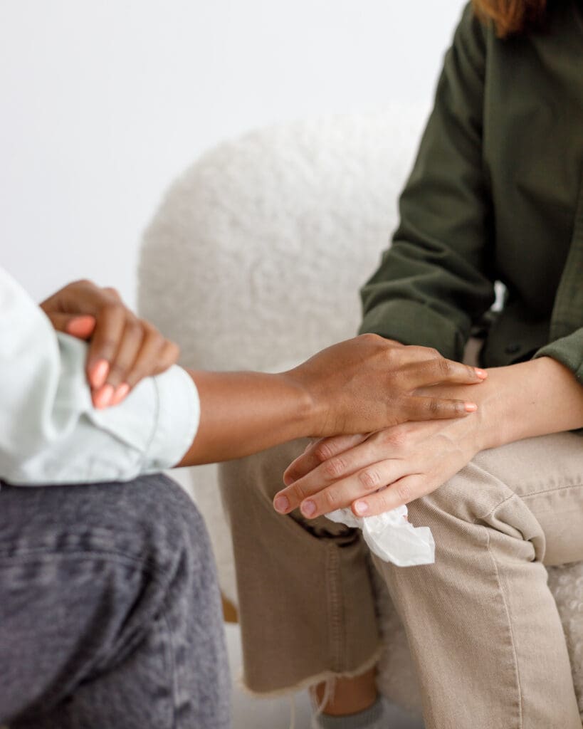 a woman sitting on a chair with a man holding her hand, representing support and care in a mental health treatment setting in New Jersey